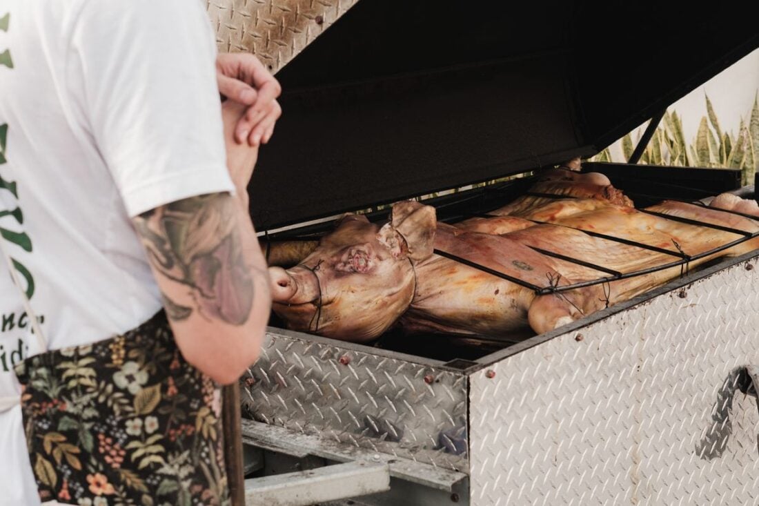 Whole pigs roasting on a large outdoor grill