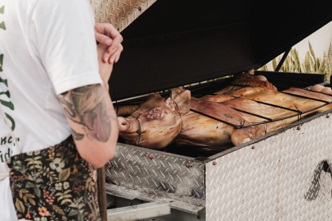 Whole pigs roasting on a large outdoor grill