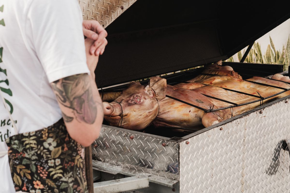 Whole pigs roasting on a large outdoor grill