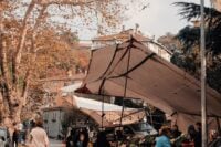 People shopping at outdoor market stalls among autumn leaves