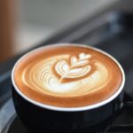 A cappuccino with latte art on a cafe table