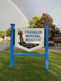 Franklin Mineral Museum entrance sign at 32 Evans Street with rainbow overhead
