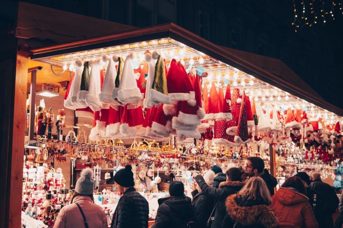 Shoppers browsing a lit Christmas market stall at night