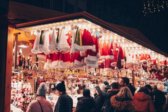 Shoppers browsing a lit Christmas market stall at night