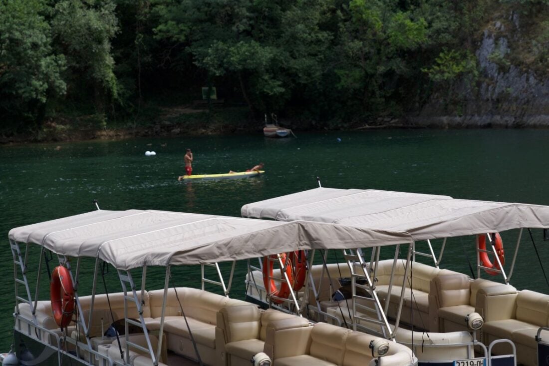 Pontoon boats docked on a lake surrounded by trees