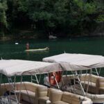 Pontoon boats docked on a lake surrounded by trees