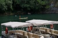 Pontoon boats docked on a lake surrounded by trees