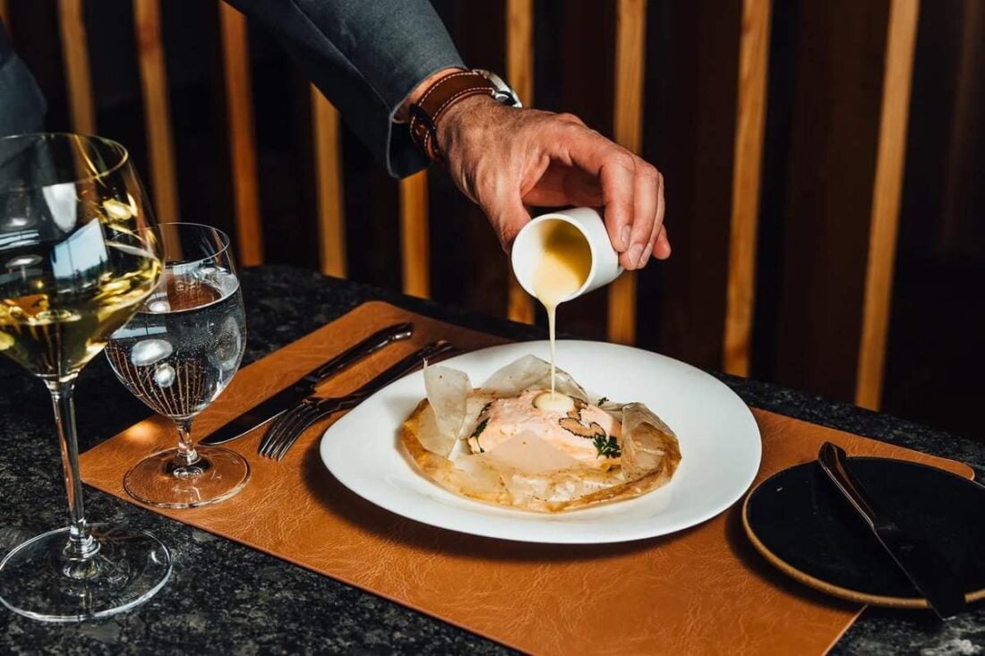 A server pours sauce over a plated course at Restaurant Latour in Hamburg, NJ