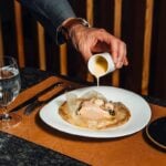 A server pours sauce over a plated course at Restaurant Latour in Hamburg, NJ