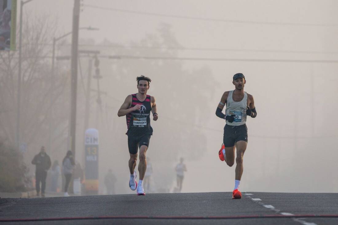 Runners leading a road race on a foggy morning