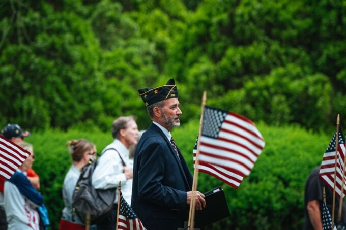 A veteran carrying an American flag at a patriotic parade